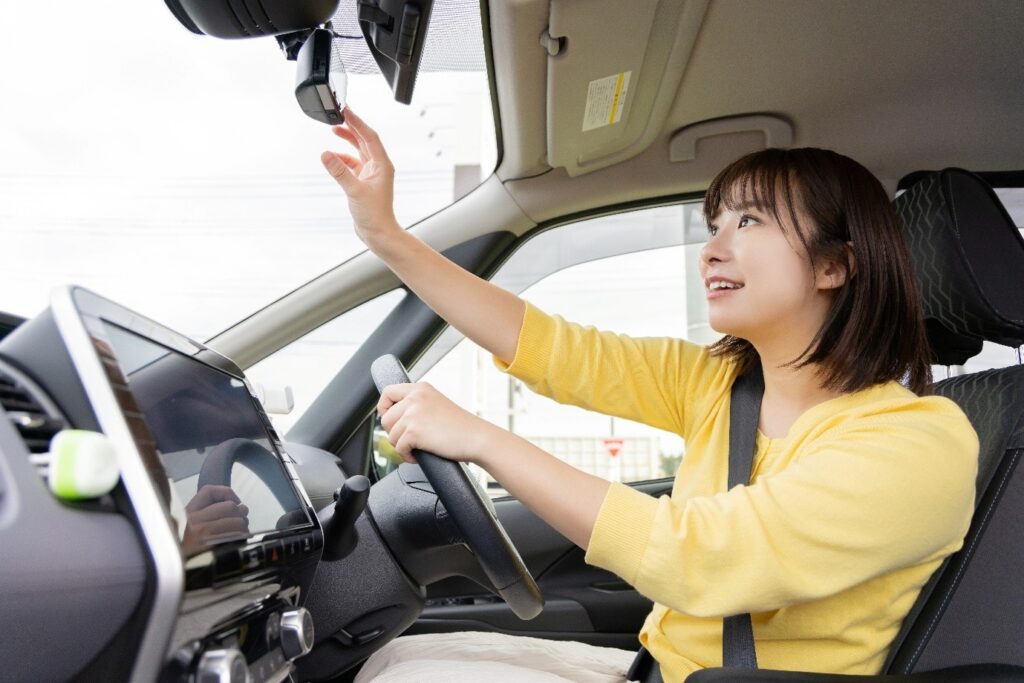 運転席にいてバックミラーを調整する女性